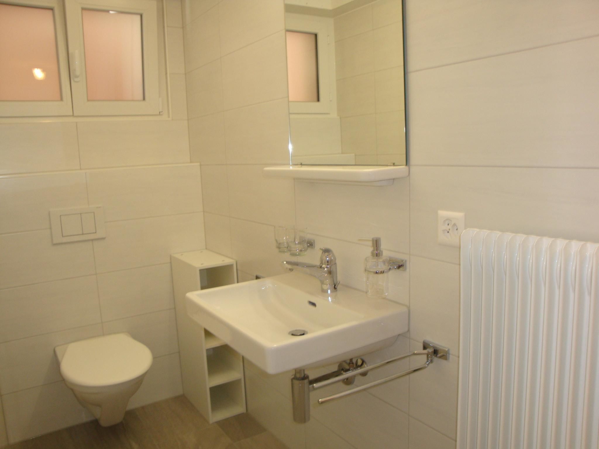 A bathroom with a toilet, sink, mirror, and towel rack.