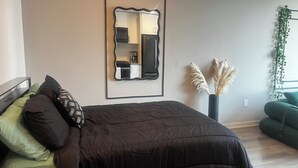 Et soveværelse med en seng, et spejl, en vase med pampasgræs og en grøn sofa.