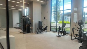 Et fitnesscenter med træningsudstyr, store vinduer og et moderne loftdesign.