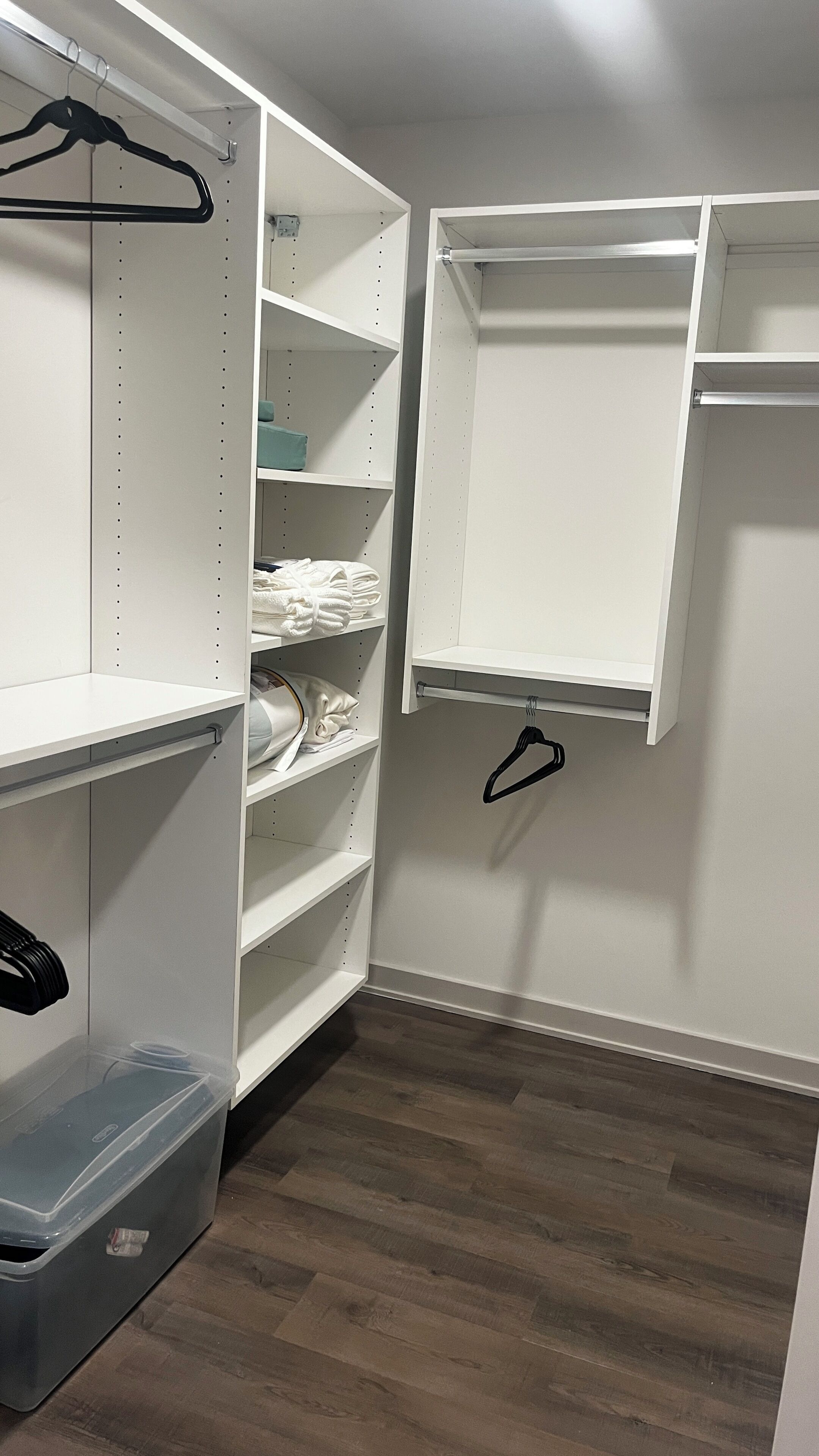 Um closet espaçoso com prateleiras abertas, uma barra para pendurar roupas e um cesto de armazenamento.