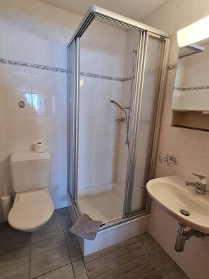 Une salle de bain avec une douche à parois de verre, des toilettes et un lavabo avec un miroir au-dessus.