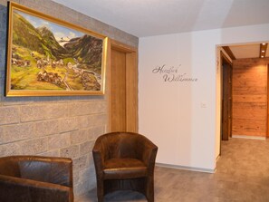 A room with a stone wall, a framed painting, a leather chair, and a wall with 'Herzlich Willkommen' written on it. - Alpenperle Appartement/Fewo 5-Bettwohnung by Interhome (Saas-Almagell)