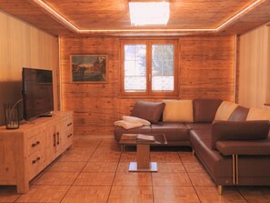 A cozy living room with wooden walls, a brown leather sofa, a wooden cabinet, and a television on the left. - Alpenperle Appartement/Fewo 5-Bettwohnung by Interhome (Saas-Almagell)