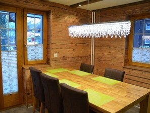Un intérieur en bois avec une grande table à manger, des chaises et un lustre.