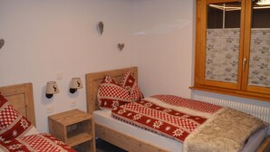 Una camera da letto con due letti, testiere in legno, un comodino, lampade a parete e una finestra con persiane.