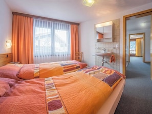A hotel room with two beds, a bathroom with a sink and mirror, and a view through the window. - Bergrose Appartement/Fewo 4-Bettwohnung Nr. 3 by Interhome (Saas-Fee)