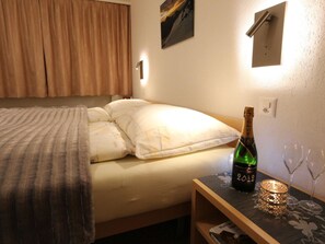 A hotel room with a bed, a bottle of champagne, two wine glasses, and a small table with a decorative item. - Azur Appartement/Fewo 2-Bettwohnung Nr. 3 by Interhome (Saas-Fee)