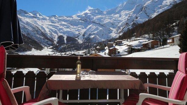 A table with a bottle and glasses, a chair, and a view of snow-covered mountains. - Azur Appartement/Fewo 2-Bettwohnung Nr. 3 by Interhome (Saas-Fee)