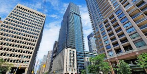 A cityscape with modern high-rise buildings, including a prominent skyscraper with a unique design. - Altitude Residences (Toronto)