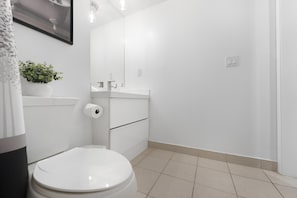 A modern bathroom with a toilet, sink, and mirror. - Altitude Residences (Toronto)