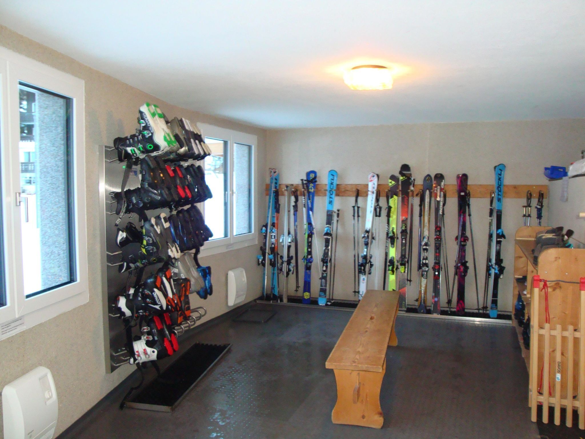 A ski rental facility with skis and ski equipment on racks, a wooden bench, and a window.