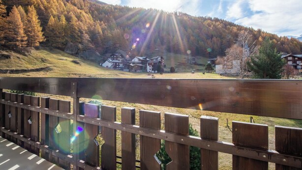 A wooden deck overlooking a lake with houses and a mountain in the background. - Haus Azur Appartement/Fewo Wohnung Nr. 1 by Interhome (Saas-Almagell)