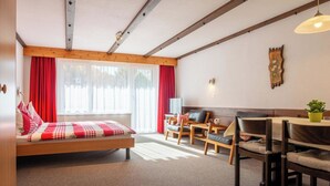 A modern room with a bed, a dining table, chairs, a TV, and a window with curtains. - Haus Azur Appartement/Fewo Wohnung Nr. 1 by Interhome (Saas-Almagell)