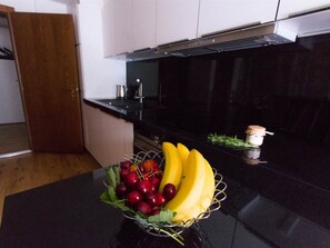 Una cocina con un frutero en la encimera, una cafetera y una botella de aceite de oliva.