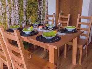 Taula de dinar de fusta amb sots plats verds, plats blancs i gots de vidre transparent.