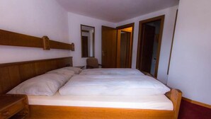 A single-bed room with a wooden headboard, a nightstand, a chair, and a wardrobe. - Monte Rosa Appartement/Fewo Appartement Strahlhorn by Interhome (Saas-Grund)