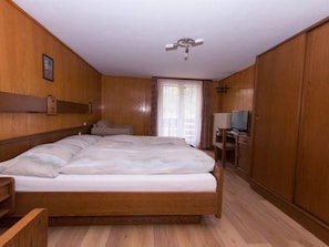 A bedroom with a wooden bed, a desk, and a television. - Monte Rosa Appartement/Fewo Appartement Strahlhorn by Interhome (Saas-Grund)