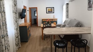 A compact living space with a dining area, a sofa, a TV, and a picture on the wall. - Villa Franca House | Rural Holiday Home with 1 Bedroom, Shared Pool and parking (Orgiva)
