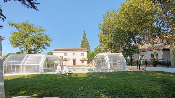A backyard with a swimming pool, covered seating, and a house in the background. - Villa Franca House | Rural Holiday Home with 1 Bedroom, Shared Pool and parking (Orgiva)