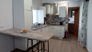 A modern kitchen with white cabinets, a marble countertop, and a built-in stove. - Villa Franca House | Rural Holiday Home with 1 Bedroom, Shared Pool and parking (Orgiva)
