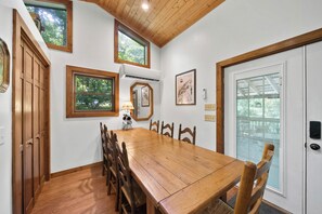 Un coin repas avec une table et des chaises en bois, une fenêtre et une porte dotée d’un panneau de verre.