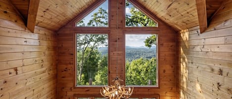 Ein Holzinnenraum mit hoher Decke, großen Fenstern und einer Kristallleuchter.