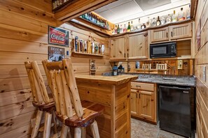 Ein Holzinterieur mit Barbereich, Holzsesseln, einem Kühlschrank und einer Mikrowelle.