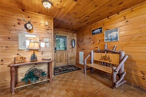 A wooden interior with a wooden bench, a wall clock, a framed map, and a door. - A Touch of Bearadise - Mountain View | Pet Friendly | Close to Town! | Game Room | Firepit | (Morganton)
