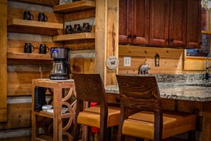 A wooden interior with a coffee maker on a table, wooden chairs, and a granite countertop. - Bear Claw Lodge - Pet Friendly | Firepit | Outdoor Fireplace | Hot Tub (Cherry Log)