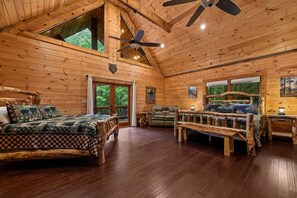 Ein rustikales Blockhaus mit einem Bett, einem Sofa, einer Bank und einem Deckenventilator.