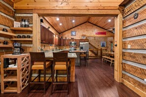 Ein Holzblockbau-Innenraum mit Küche, Essbereich und einer Treppe zu einer oberen Ebene.