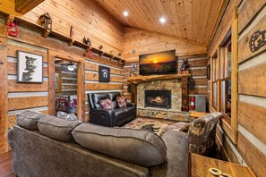 Ein gemütliches Blockhaus-Interieur mit Kamin aus Stein, Ledersofas und Holzwänden.