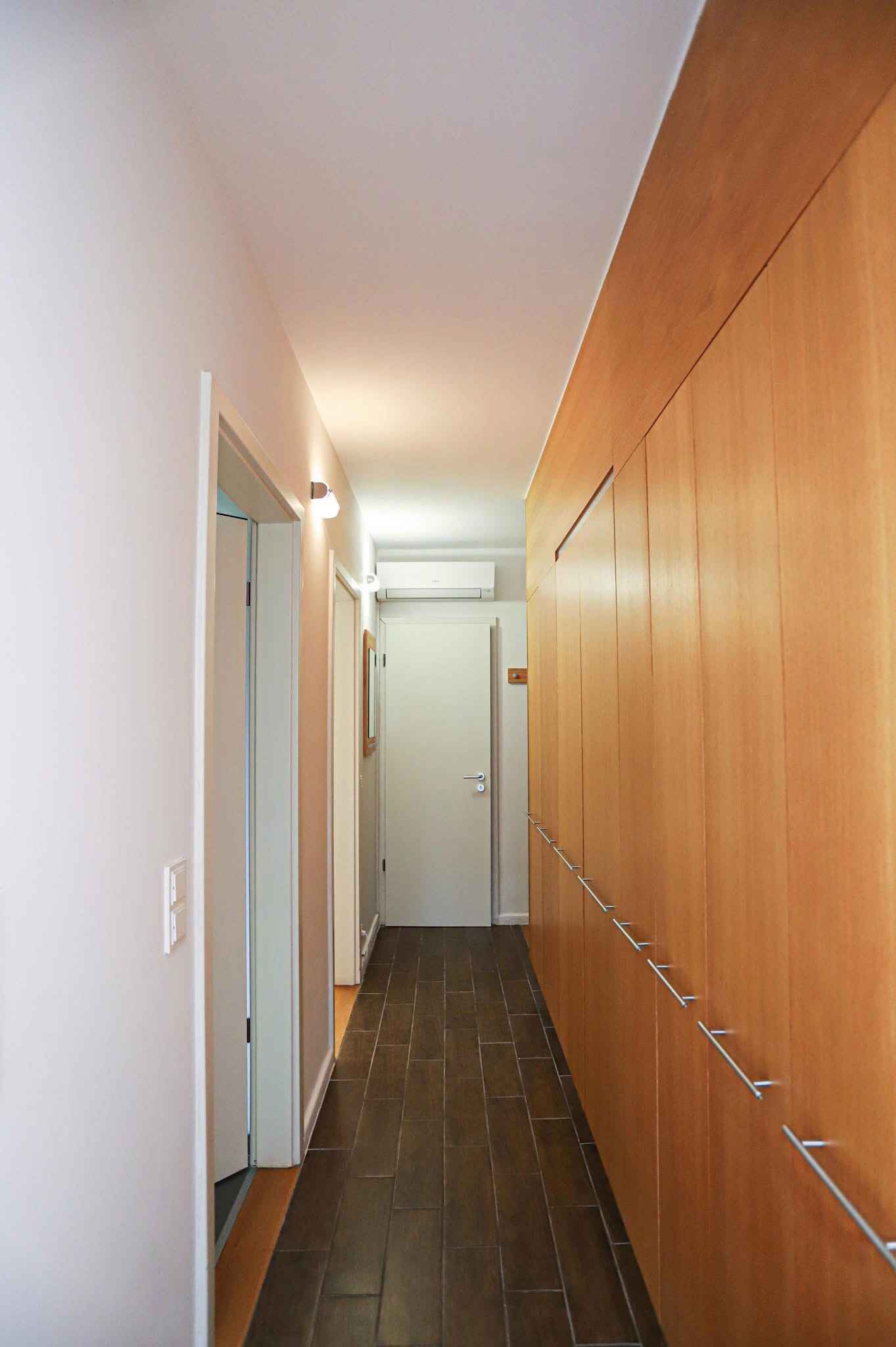 Un couloir étroit, avec un lambris en bois sur un côté et une porte blanche au fond.