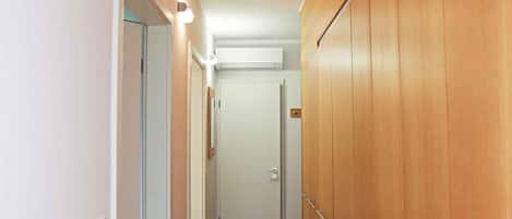 Un pasillo estrecho con paneles de madera en una pared y una puerta blanca al final.