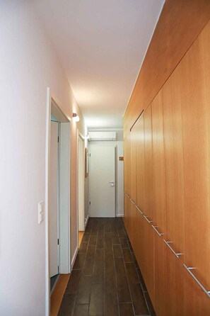 Ein schmaler Korridor mit Holzvertäfelung an einer Seite und einer weißen Tür am Ende.