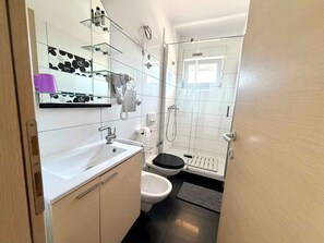 A compact bathroom with a sink, toilet, and shower. - Modern holiday apartment with balcony (Jadranovo)
