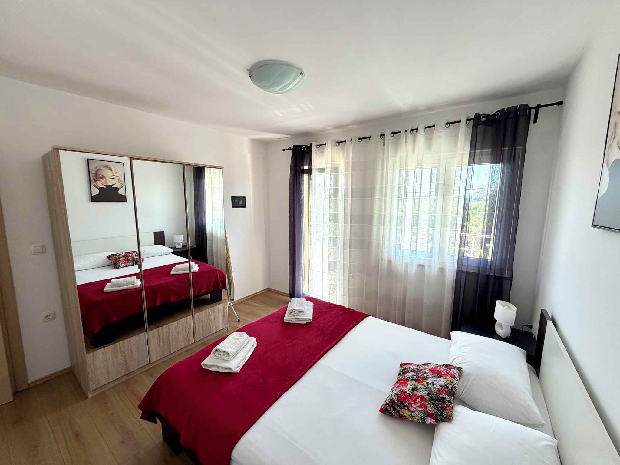 A hotel room with a bed, a mirror, a wardrobe, a window with curtains, and a ceiling light.
