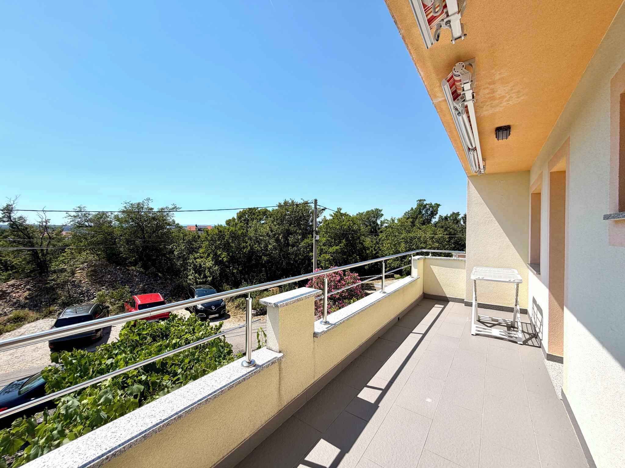 A balcony with a metal railing, a small table, and a chair.