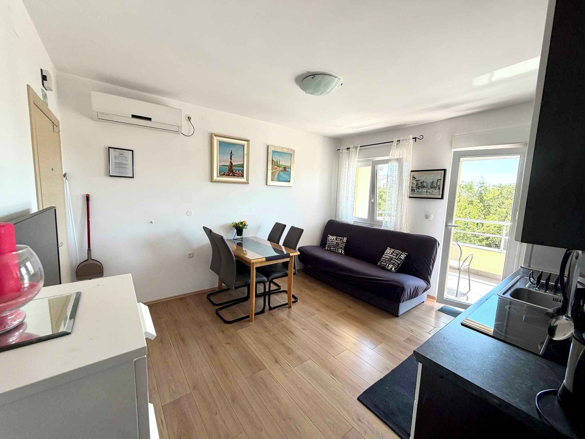 A modern living space with a dining area, a sofa, a kitchen, and a balcony with a view.