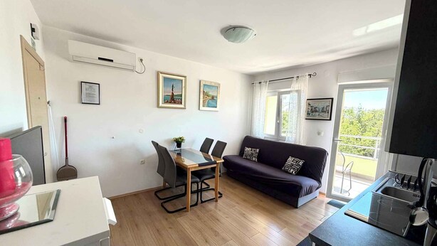 Ein moderner Wohnraum mit Essbereich, Sofa, Küche und einem Balkon mit Aussicht.