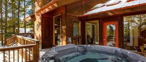 Una cabaña de madera con jacuzzi, terraza y puertas de vidrio.