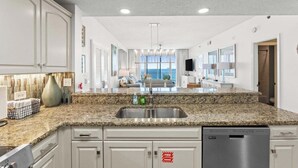 A kitchen with granite countertops, white cabinetry, a stainless steel sink, and a dishwasher. - 805 Gulf Front Views & Rare Gulf Front Pool ~ Gorgeous 2-bdm ~ Book Sept 28th (Destin)