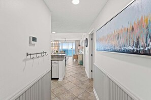 Un couloir donnant sur un espace cuisine, un coin repas avec vue et un grand tableau abstrait accroché au mur.