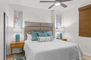 Ein Schlafzimmer mit einem Bett, zwei Nachttischen, einem Deckenventilator und abstrakter Wandgestaltung.
