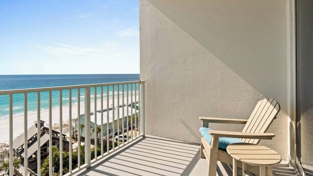A balcony with a view of the beach and ocean, a wooden chair, and a small table. - 805 Gulf Front Views & Rare Gulf Front Pool ~ Gorgeous 2-bdm ~ Book Sept 28th (Destin)