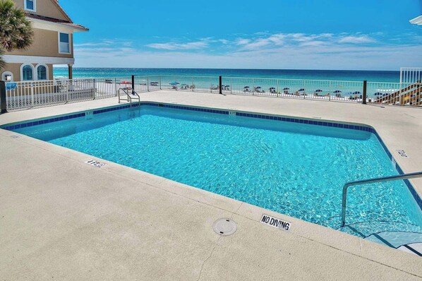 A rectangular swimming pool with a 'NO DIVING' sign, surrounded by a white fence, with a view of the ocean and a building in the background. - 805 Gulf Front Views & Rare Gulf Front Pool ~ Gorgeous 2-bdm ~ Book Oct 23rd (Destin)