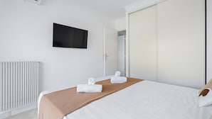 Ein Hotelzimmer mit Bett, Flachbildfernseher, Kleiderschrank und Heizkörper.