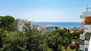 Ein Küstenwohngebiet mit mehrstöckigen Gebäuden, einige davon mit Balkonen, und freiem Blick auf das Meer.