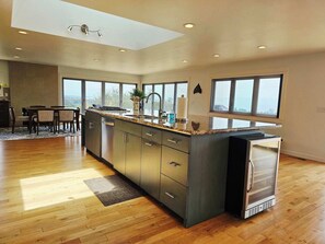 A modern kitchen with a large island, built-in appliances, and large windows offering views. - Pool Sea and Sunshine (Aptos)