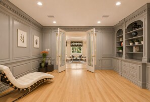 A spacious room with a chaise lounge, a dining area with a sofa, and a view of a garden through a window.